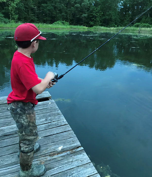 A Fishing Boy on a River Holds a Fishing Rod, a Child Caught a